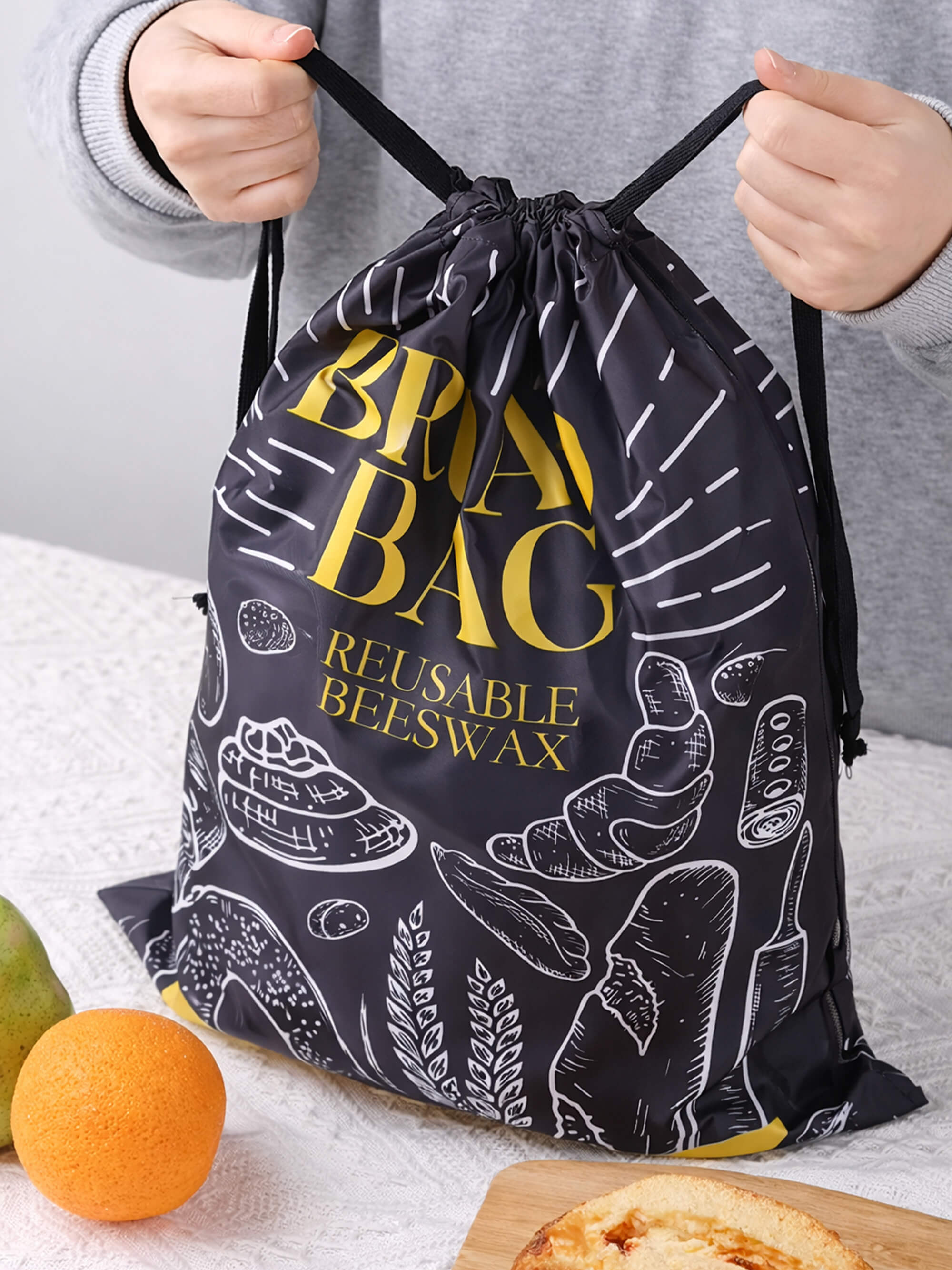 Reusable beeswax bread bag with drawstring closure being tightened for secure food storage