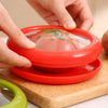 Reusable silicone tomato saver container being sealed by hand on wooden chopping board, keeping cut tomato fresh and reducing food waste in kitchen storage