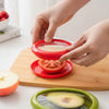 Silicone food saver lid covering half a tomato on a kitchen board for fresh storage